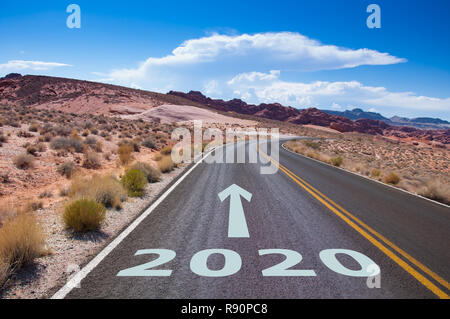 The year 2020 written on an empty street in the desert of Nevada, USA. An arrow is pointing into the future. Stock Photo