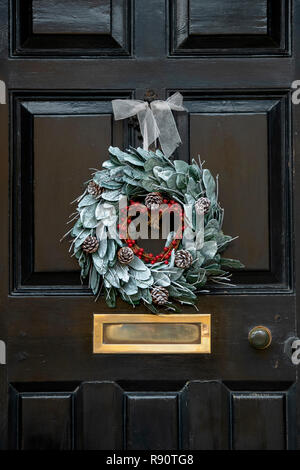 Christmas wreath on a black painted wooden house door in Chipping campden. Cotswolds, Gloucestershire, England Stock Photo