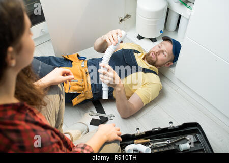 Young plumber changing trap under sink Stock Photo
