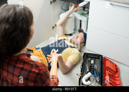 Handsome plumber fixing sink pipe Stock Photo