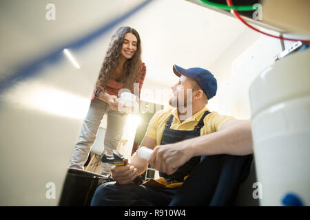 Pretty home owner giving coffee to plumber Stock Photo