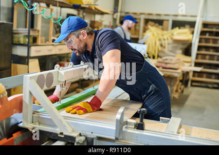 Young furniture worker fixing wooden plank Stock Photo