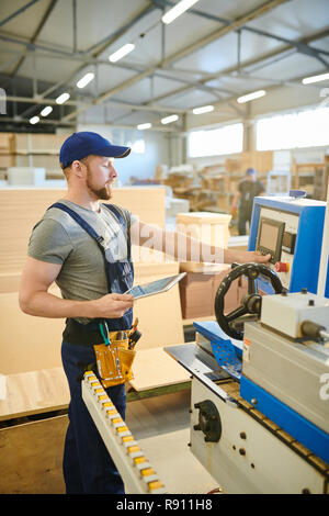 Confident male worker using computer of factory machine Stock Photo