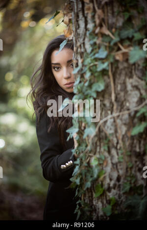 Beautiful woman hiding behind a tree Stock Photo