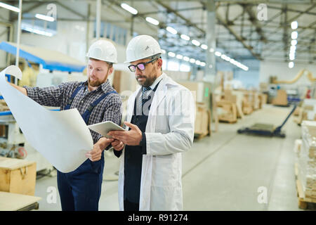 Engineers in hardhats working with project blueprint Stock Photo