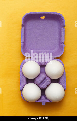 Easter composition. Set of Four white eggs in purple box on  yellow background Stock Photo