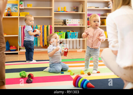 babies children playing in kindergarten with a teacher Stock Photo