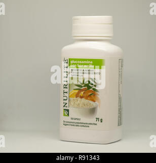 CAGLIARI,ITALY -DECEMBER 2018: Containers and Pile of capsules Glucosamine with Boswellia on white background. Nutrilite natural and vegan supplements Stock Photo