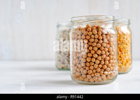 Glass jar of healthy dried chickpeas in a receding line with other jars of legumes over a white background with copy space Stock Photo
