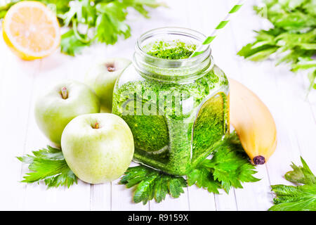 Fresh green smoothie with banana, apples, celery and lemon on white table Stock Photo