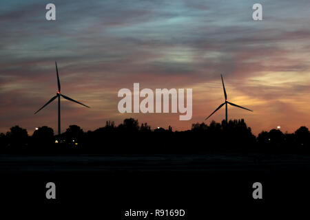 Two modern windmills silhouetted against the evening sky. Beautiful colors in the sky after sunset at blue hour. Stock Photo