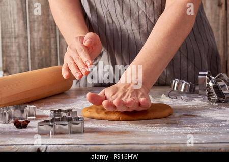 Woman hands rolls up the gingerbread dough on the table Stock Photo