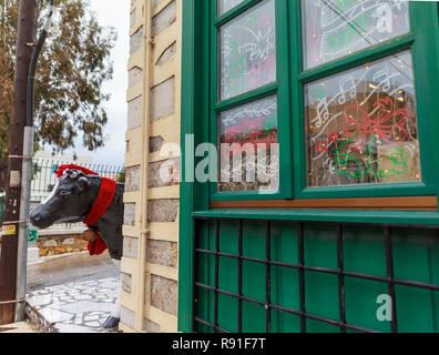 Ermoupolis: December 18th . Street photography outside butcher's shop in downtown Ermoupolis displaying a fake bull in Santa hat and scarf. Ermoupolis Stock Photo