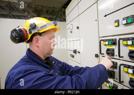 An electrician working a control panel in Krafla geothermal power station, that measures some of the 5000 measurements that control the power plant.. Krafla has an installed capacity of 60 MW. 100% of Iceland's electricity is produced from renewables, 70% from hydro and 30% from geothermal. Stock Photo
