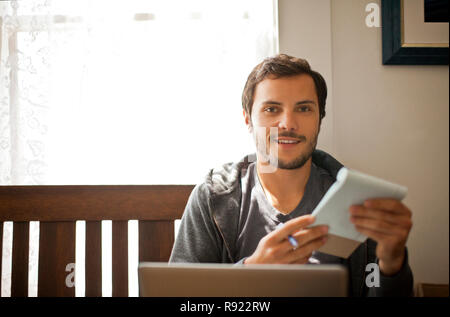 Portrait of a smiling young man studying in his living room. Stock Photo