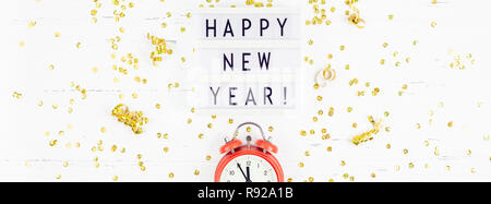 New Year or Christmas pattern flat lay top view red alarm clock twelve midnight Xmas holiday celebration white wooden golden sparkles confetti backgro Stock Photo