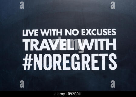 Live with no excuses travel with no regrets message written on capital white letters on a black background. #no regrets hashtag Stock Photo