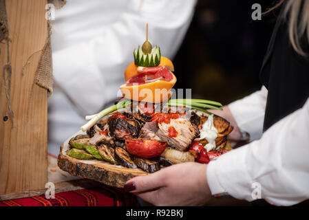 Baked potatoes with vegetables and fruits on wooden stand, delicious dish in restaurant. Stock Photo