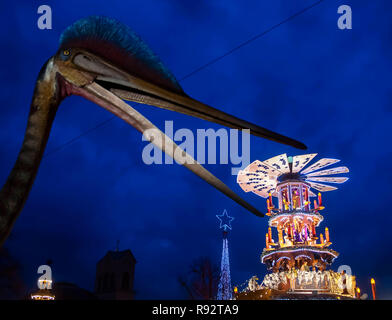 Karlsruhe, Germany. 19th Dec, 2018. In front of the State Museum of Natural History stands a life-size model of a Hatzegopteryx giant flying dinosaur. At the beak you can see the top of a Christmas pyramid, which is placed on the adjacent Christmas market. Credit: Uli Deck/dpa/Alamy Live News Stock Photo