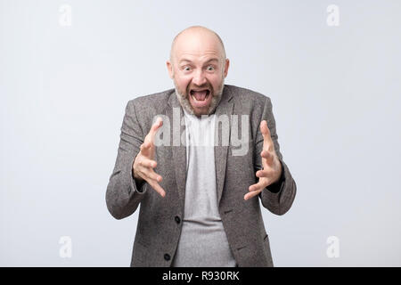 Peevish annoyed man gestures angrily, expresses negative emotions, screams fron irritation. Stock Photo