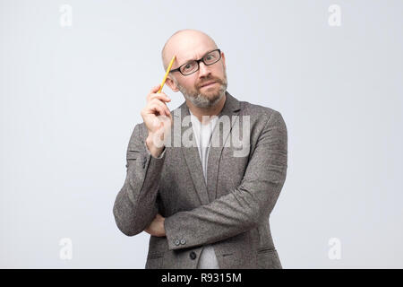 European man is thinking about something scratching his face with pencil Stock Photo