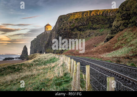 This is a picture of the railtracks that run along the Antrim Coast.  In the distance you can see Mussenden Temple on the edge of the cliff Stock Photo