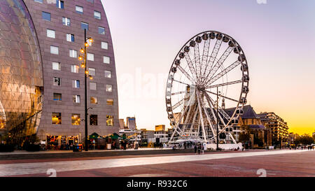 Modern Ferris Wheel with the Medieval Saint Laurens Church in the background in the center of Rotterdam near Market Hall square at Dusk in  Holland Stock Photo