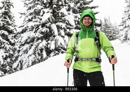 Smiling man walking on winter trek in white snowy forest, looking at camera. Man hiking in winter woods. Travel and healthy lifestyle outdoors in beau Stock Photo
