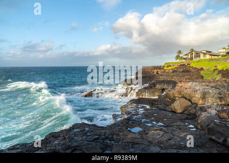 Ocean surf hitting the basalt cliff as water from previous wave back flashing to the sea, Kauai, Hawaii Stock Photo