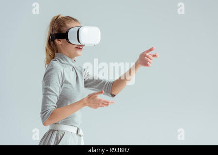 surprised woman gesturing while having virtual reality experience isolated on grey Stock Photo