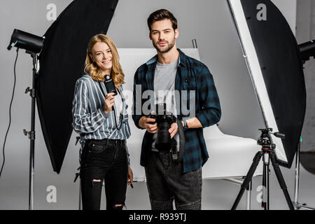 young photographers with professional equipment standing together and smiling at camera in photo studio Stock Photo