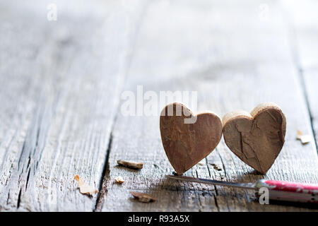 Couple carved wooden hearts and knife abstract love valentines background with free space Stock Photo