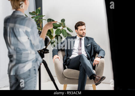 cropped shot of young photographer shooting handsome male model in studio Stock Photo