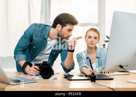 young photographers using digital devices and retouching photos at workplace Stock Photo