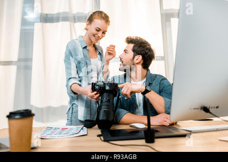 professional young photographers using camera and smiling each other at workplace Stock Photo