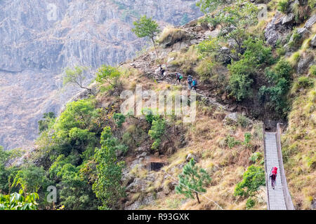 Trekkers crossing a suspension foot bridge on the Manaslu Circuit Trek, Nepal Himalayas Stock Photo