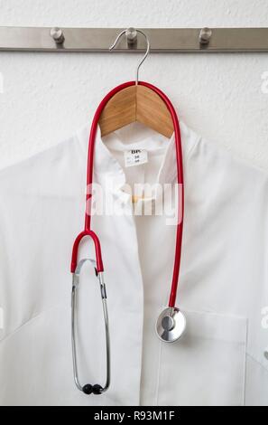 Doctor's coat hanging on a coat hanger on a coat rack, with a stethoscope Stock Photo