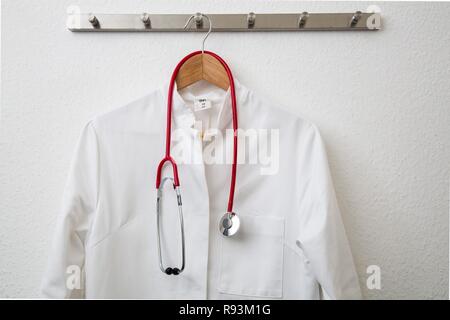 Doctor's coat hanging on a coat hanger on a coat rack, with a stethoscope Stock Photo