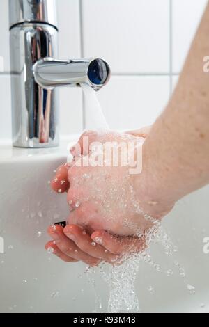 Person washing their hands under running water from a faucet, symbolic image for water consumption Stock Photo