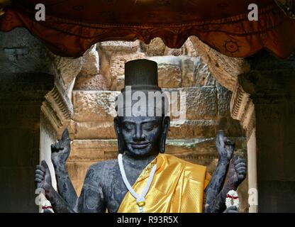 Multi armed buddha with golden sash and white flowers in Cambodia Stock Photo