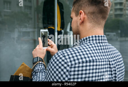 Man taking a photo of a shop window of a fashion store Stock Photo