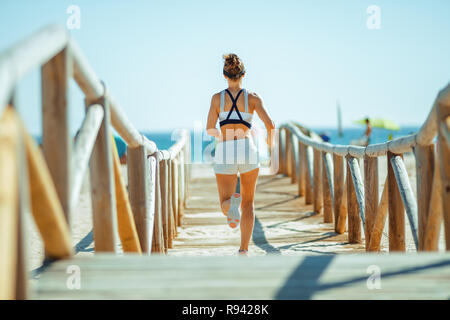 seen from behind fit woman jogger in fitness clothes on the seacoast jogging. Perfect environment to being mindful, reduce stress and keep your body i Stock Photo