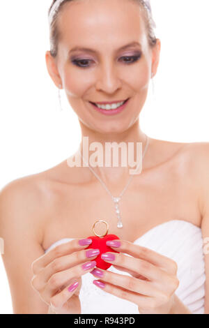 Excited happy bride holding showing engagement ring box. Surprised woman in white wedding dress isolated on white background. Stock Photo
