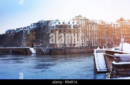 Seine river embankment with trees and buildings in snow, Paris, France Stock Photo