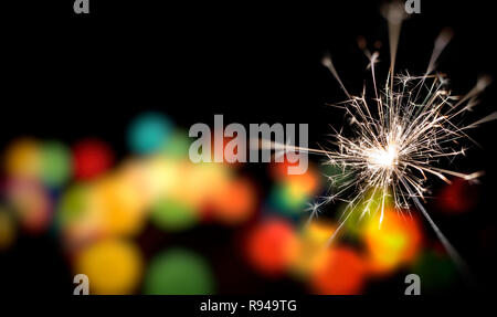 Bengal fire is burning against the background of the Christmas and New Year's multi-colored lights. Stock Photo