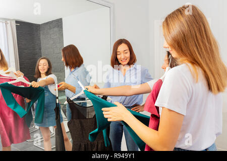 Portrait of mother helping her teenage daughters to choose going out outfit at home Stock Photo