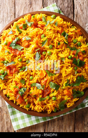 Vegetarian Indian rice with vegetables close-up on a plate on the table. Vertical top view from above, rustic style Stock Photo