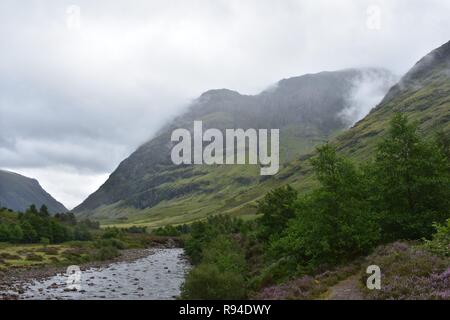 The River Coe Flowing Through The Valley of The Glencoe Mountain Range in The Scottish Highlands. Taken on a Raining and Overcast August Day. Stock Photo