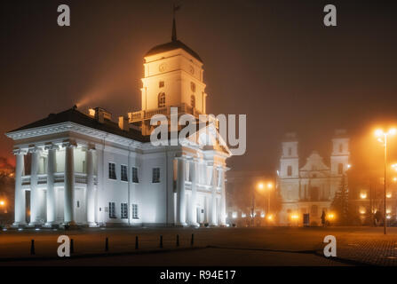 View of the Town Hall and Cathedral of the Holy Name of Mary in the fog in Minsk at night, Belarus Stock Photo