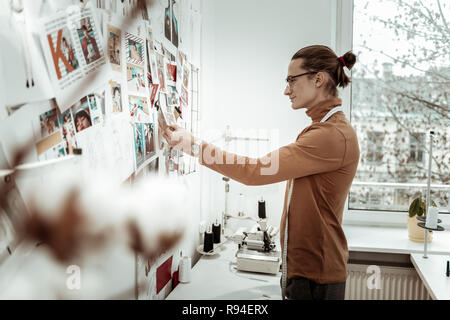 Young fashion dressmaker in a brown garment smiling positively Stock Photo